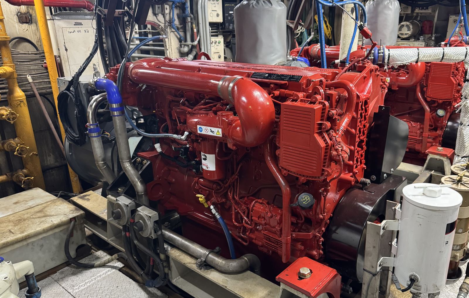 A red diesel engine in an engine room, with a second one beside it